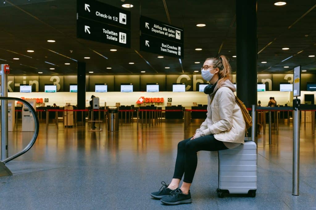 A girl in a mask sitting at the airport